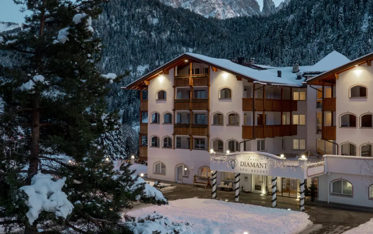 Diamant Spa Resort in St. Christina – Beleuchtete Außenansicht im Winter mit Dolomiten-Panorama | Wellnesshotel Südtirol