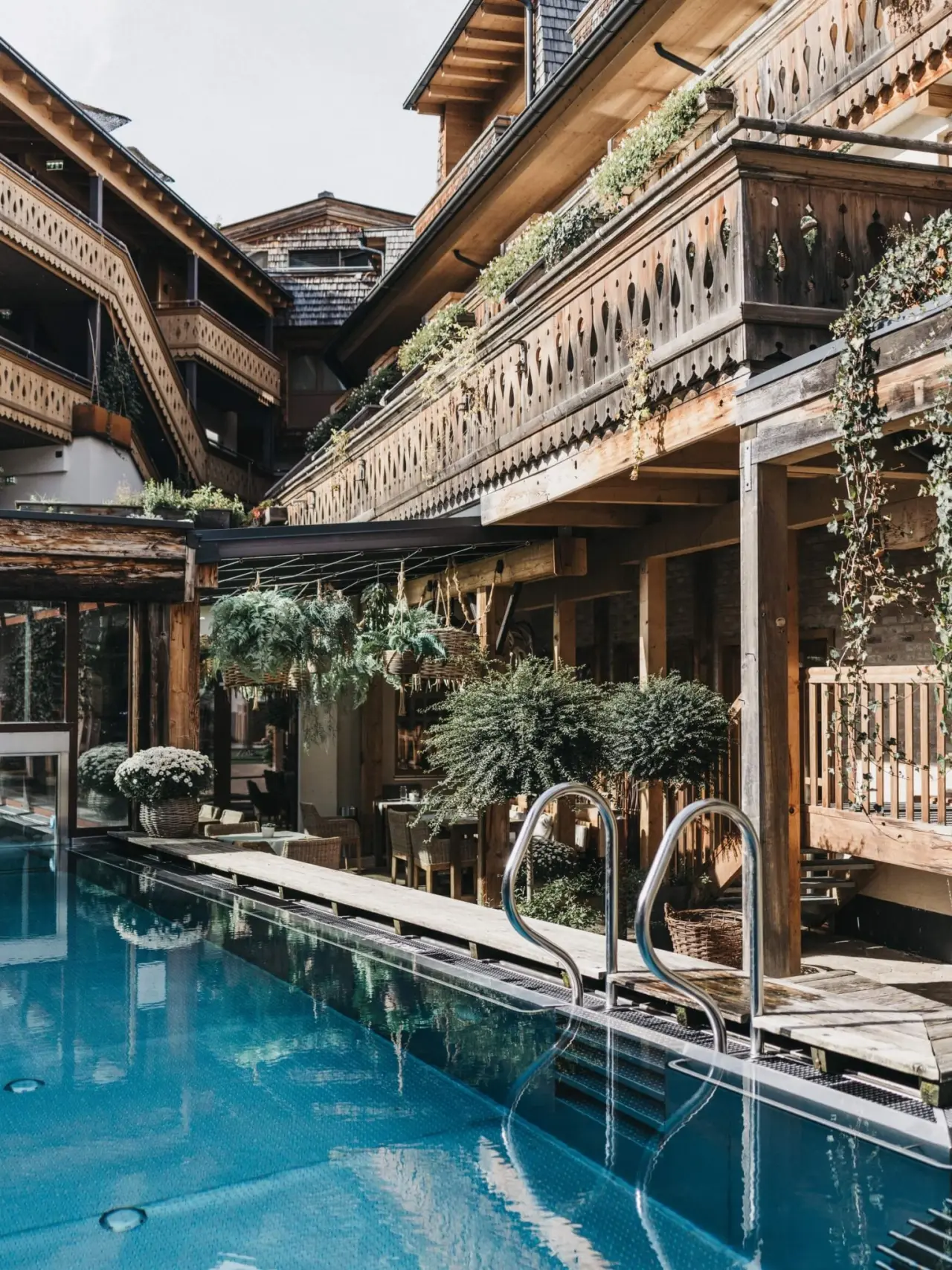 Einladender Aussenpool mit traditioneller Holzarchitektur und üppiger Bepflanzung im Lifestyle-Hotel Eder.