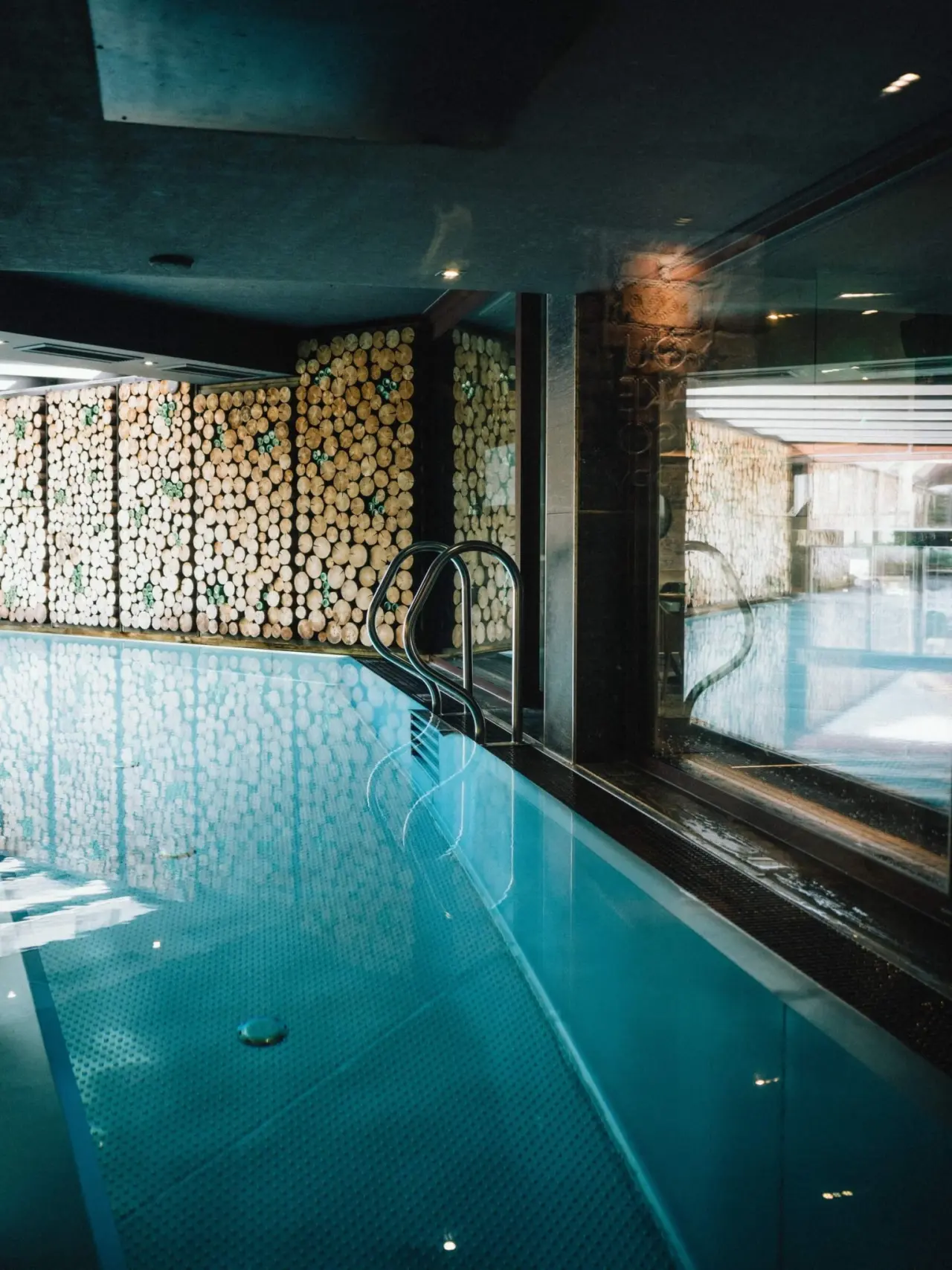 Innenpool mit natürlicher Holzstapelwand im Wellnessbereich des Lifestyle-Hotel Eder.