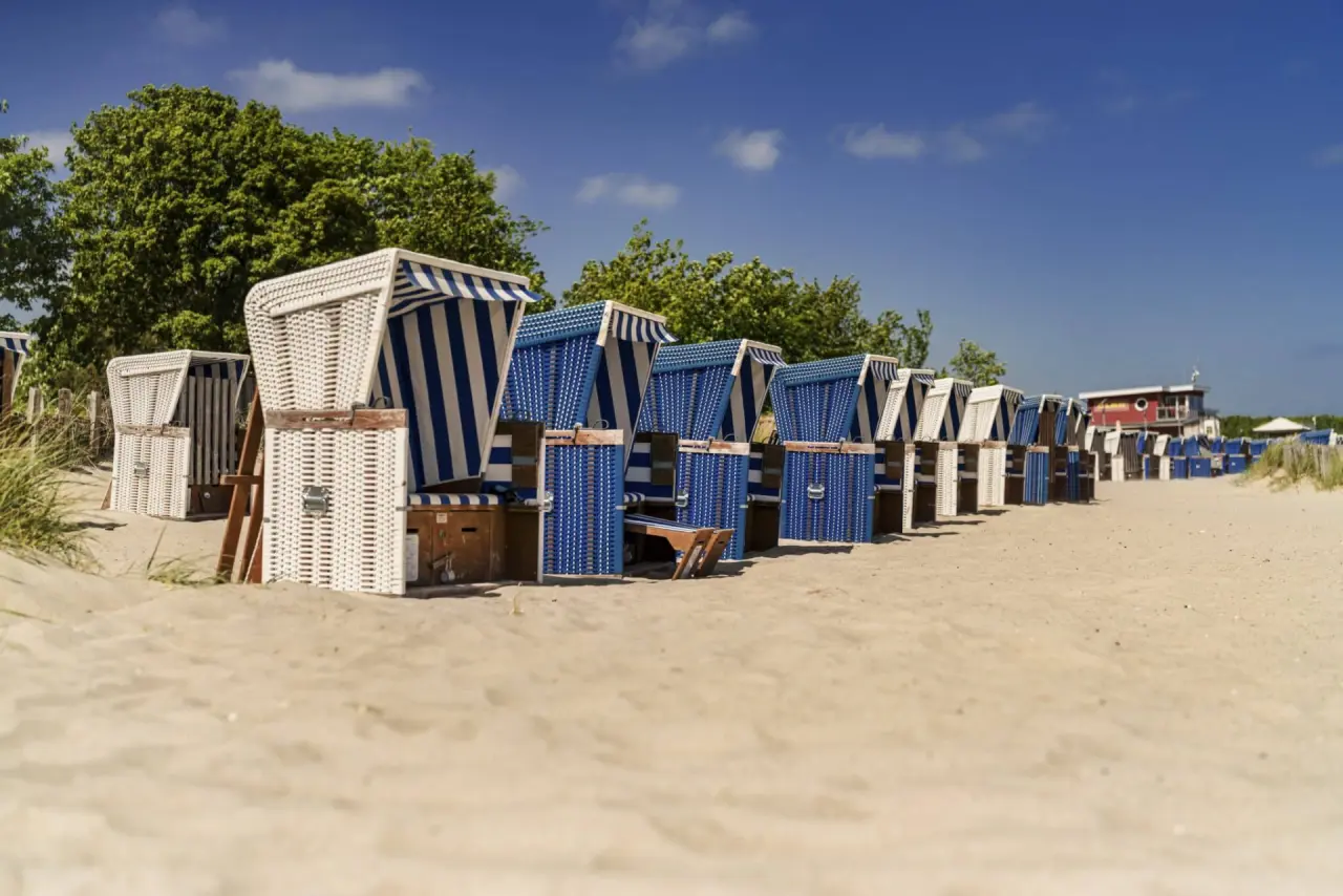 Reihe von blauen und weißen Strandkörben am Sandstrand der Ostsee in Dampland, nahe dem Ostseehotel Midgard.