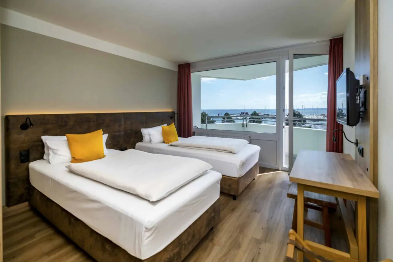 Helles Hotelzimmer mit zwei Betten und Meerblick im Ostseehotel Midgard in Dampland.