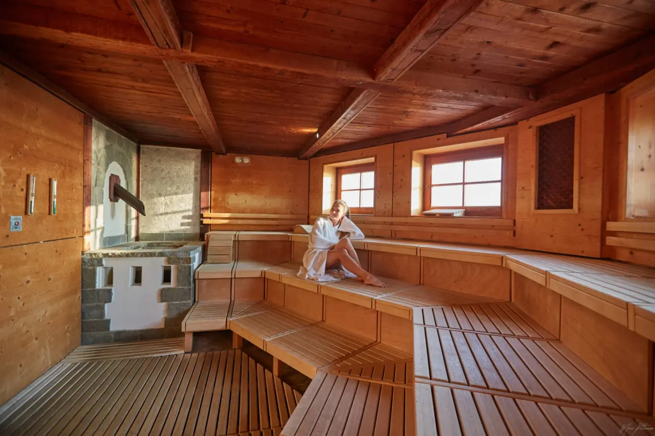 Traditionelle Holzsauna mit entspannter Person und Blick nach draußen im Ostseehotel Midgard in Dampland.
