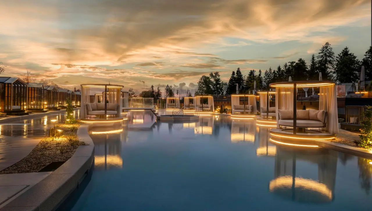 Luxuriöser Outdoor-Poolbereich bei Sonnenuntergang mit beleuchteten Daybeds im Das Stemp****S Wellnessresort.