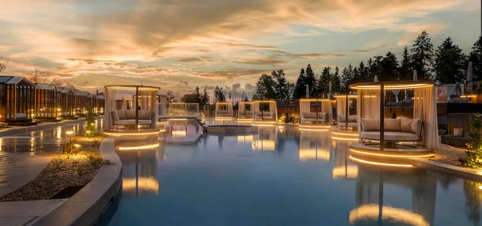 Das Stemp****S Wellnessresort in Büchlberg – Außenpoolbereich mit beleuchteten Daybeds bei Sonnenuntergang | Wellnesshotel Bayerischer Wald
