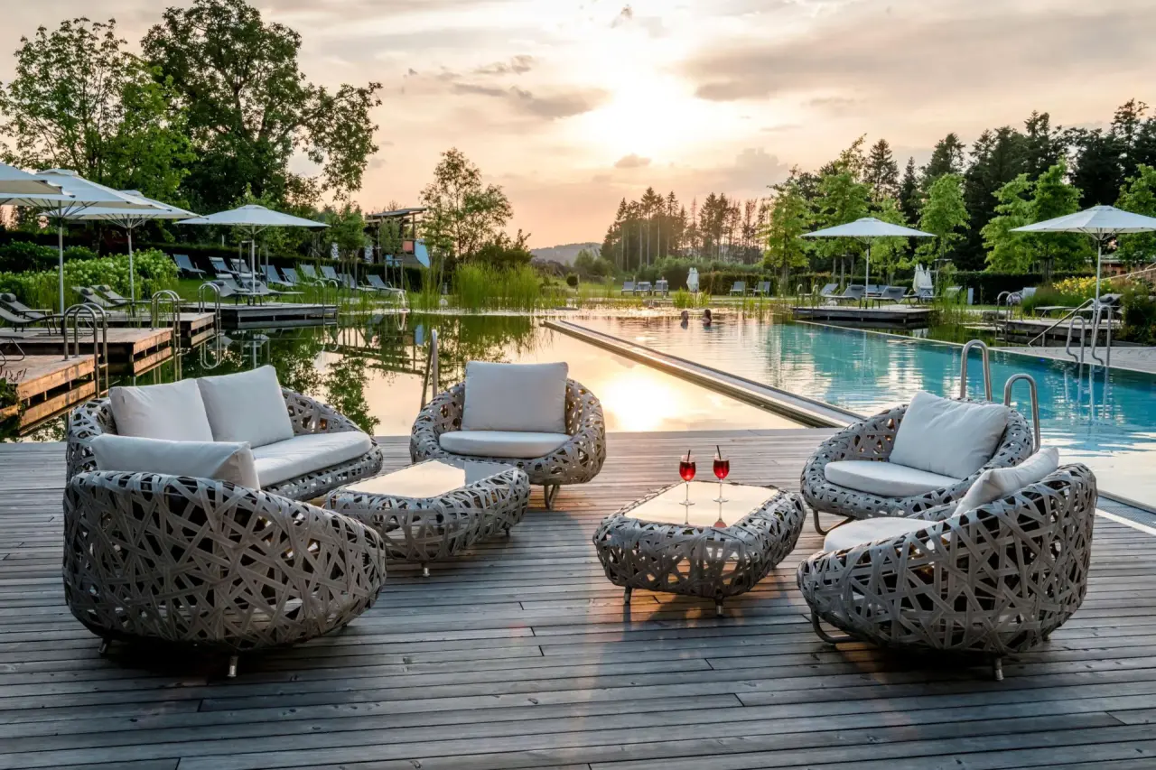 Romantische Abendstimmung am Aussenpool und Naturbadeteich mit Lounge-Möbeln im Das Stemp****S Wellnessresort.