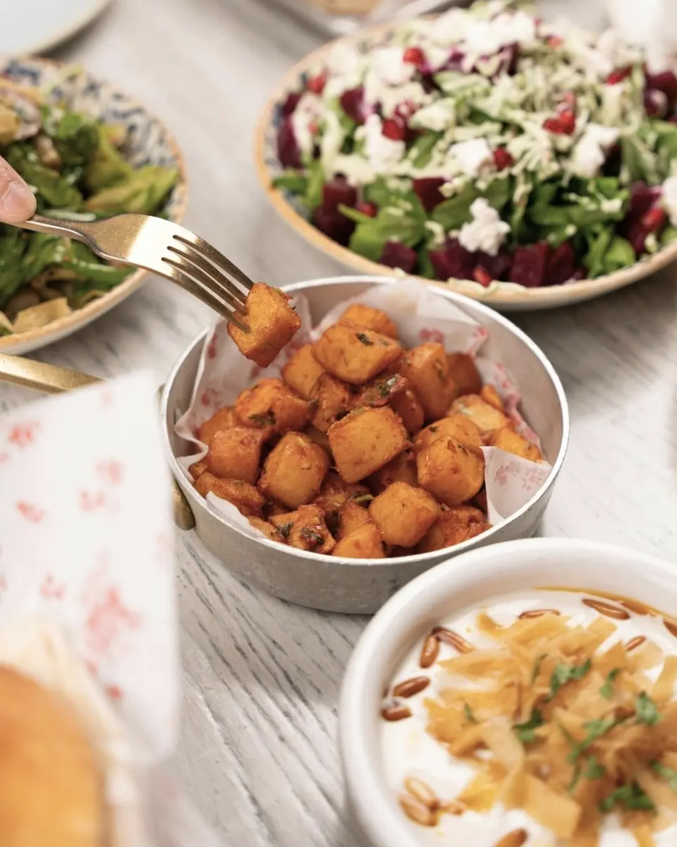 Appetitliche Speisen wie knusprige Kartoffelwürfel, frischer Salat und cremiger Dip im Restaurant des Logierhus Langeoog.