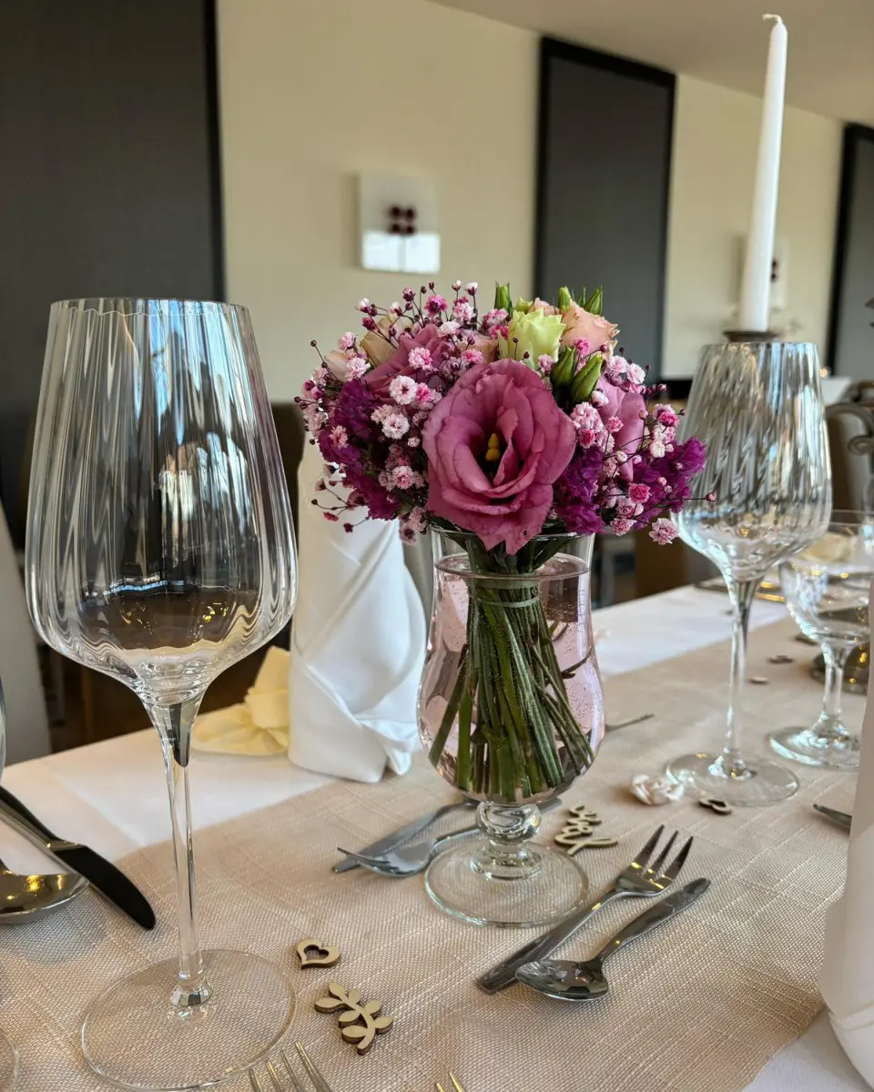 Festlich gedeckter Tisch mit frischen Blumen und eleganten Weinglaesern im Restaurant des Logierhus Langeoog.