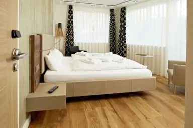 Modernes Doppelzimmer mit Holzboden und großen Fenstern im Logierhus Langeoog.
