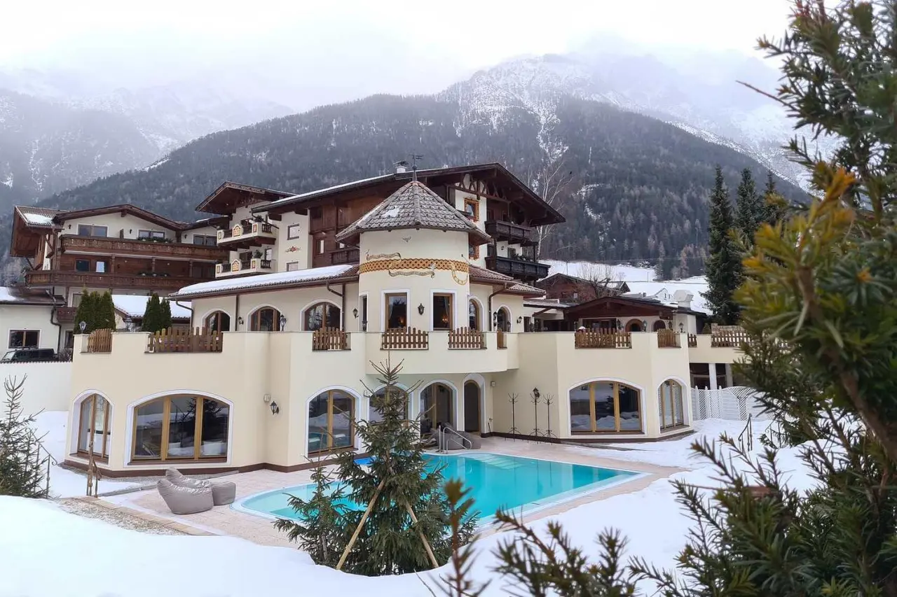 Aussenansicht von Forster's Naturresort mit beheiztem Aussenpool im Schnee und verschneitem Bergpanorama.