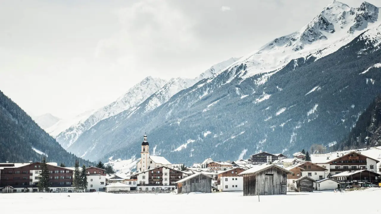 Idyllisches Winterpanorama eines verschneiten Bergdorfs in den Alpen, perfekte Kulisse für das Vitalhotel Edelweiss.