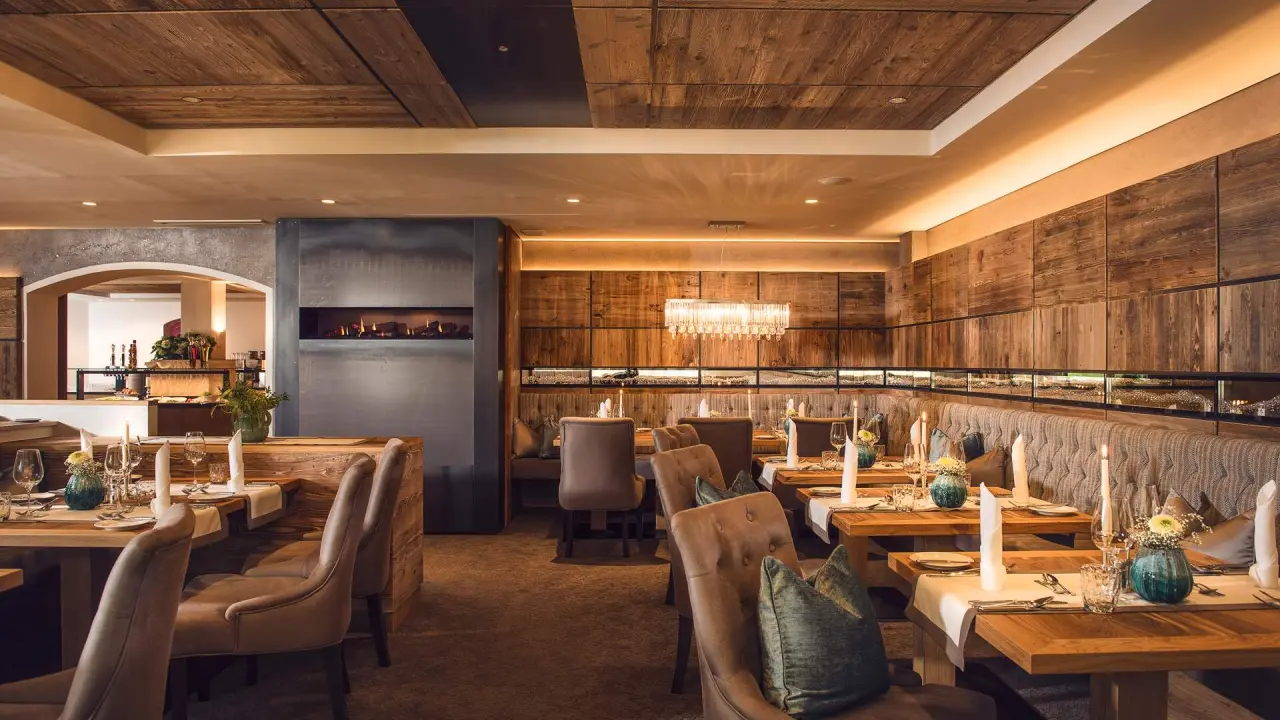 Gemütliches Restaurant im Vitalhotel Edelweiss mit Holzelementen, Kamin und elegant gedeckten Tischen.