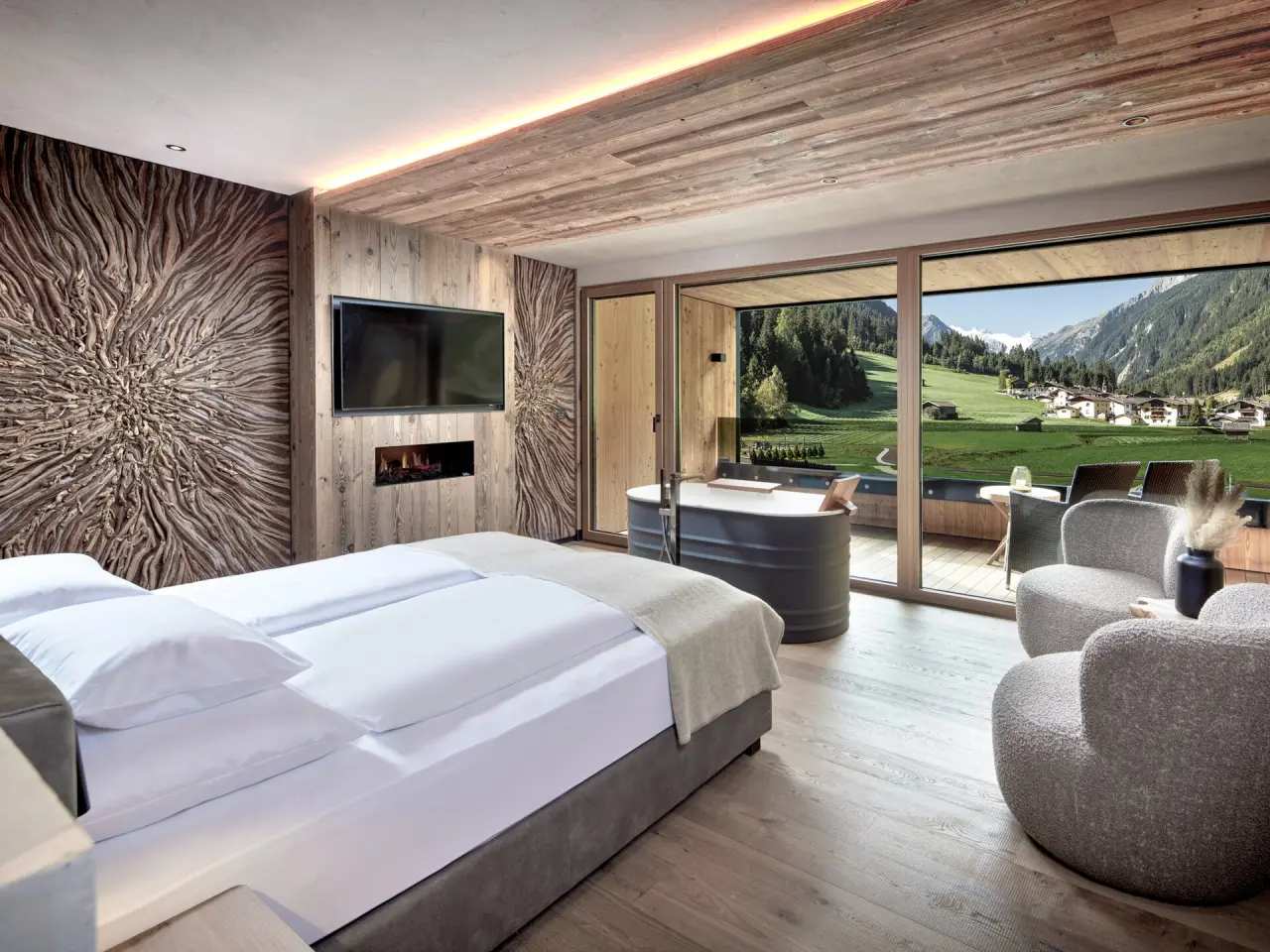 Luxuriöses Hotelzimmer im Vitalhotel Edelweiss mit Bergblick, Kamin und privater Badewanne auf dem Balkon.