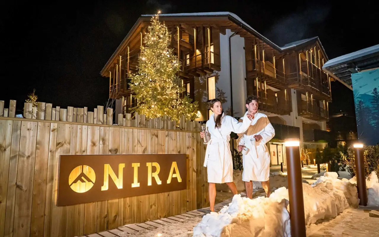 Nira - Mountain Resort Futura in Sondalo – Beleuchtete Außenansicht mit Gästen im Bademantel | Wellnesshotel Lombardei
