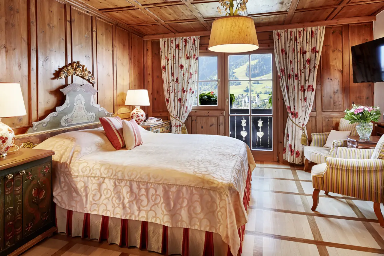 Gemütliches Doppelzimmer mit Holzeinrichtung, traditionellem Bett und Bergblick im Tennerhof Gourmet & Spa de Charme Hotel.
