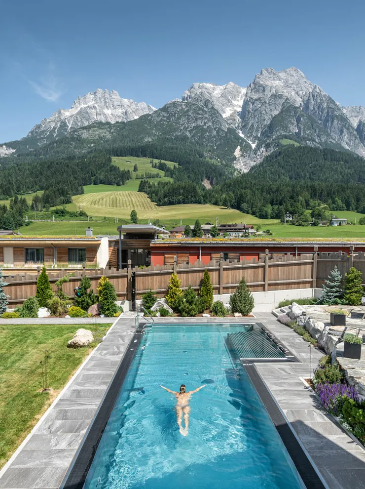 Good Life Resort Riederalm in Leogang – Außenpool mit Schwimmer und Bergpanorama | Wellnesshotel Salzburger Land