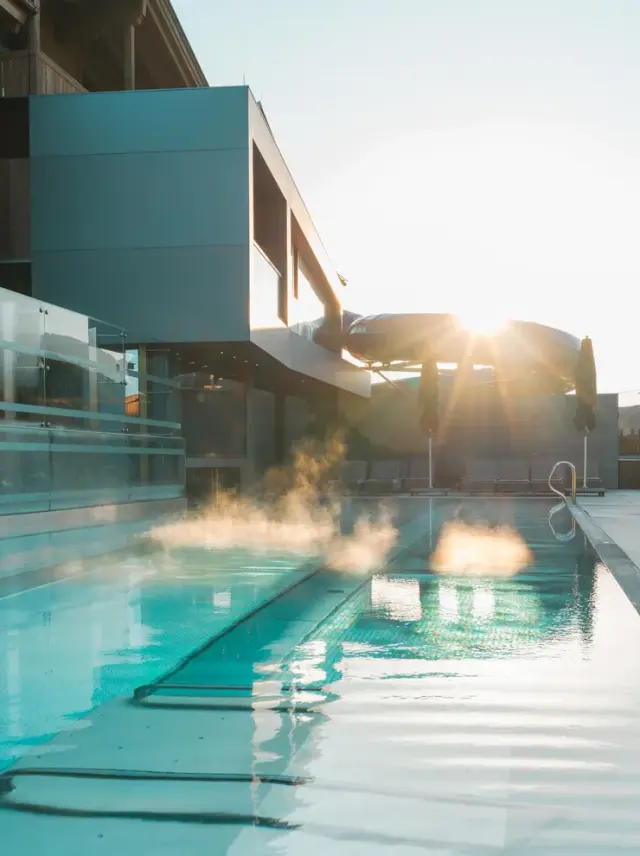 Good Life Resort Riederalm in Leogang – Beheizter Außenpool mit aufsteigendem Dampf am Morgen | Wellnesshotel Salzburger Land