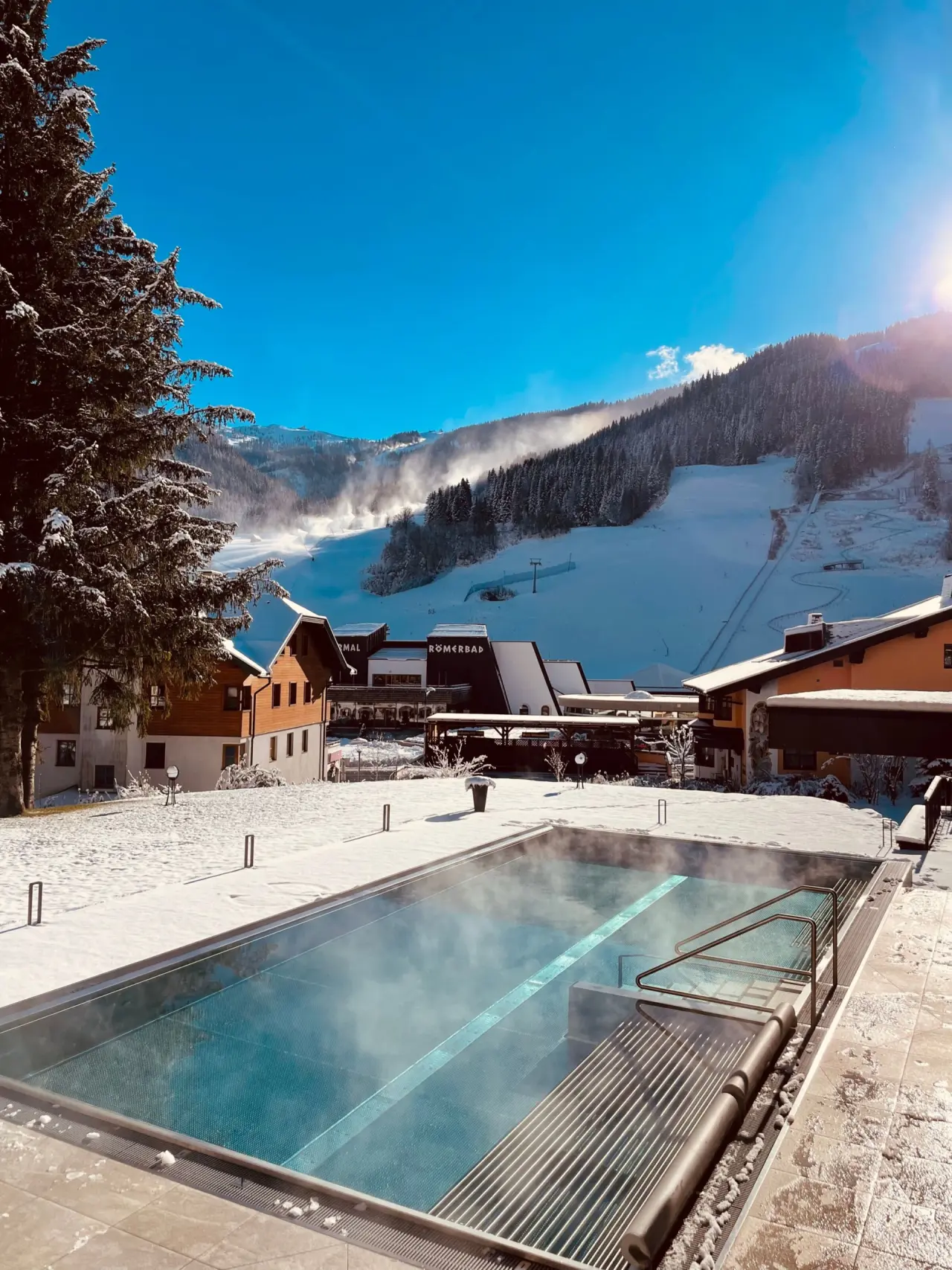 Beheizter Aussenpool mit Dampf im winterlichen Schnee und Bergpanorama am Evident Hotel Prägant****.