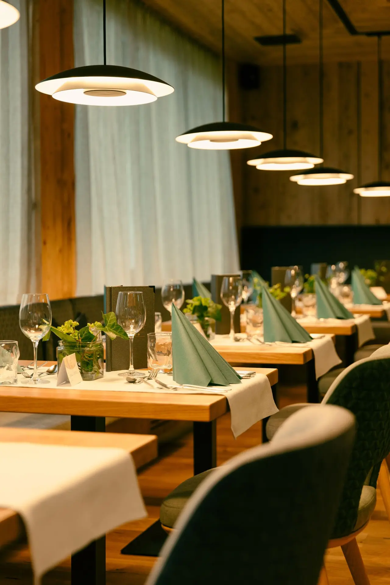 Elegant gedeckte Tische im Restaurant des Evident Hotel Prägant mit warmem Licht und stilvoller Dekoration.