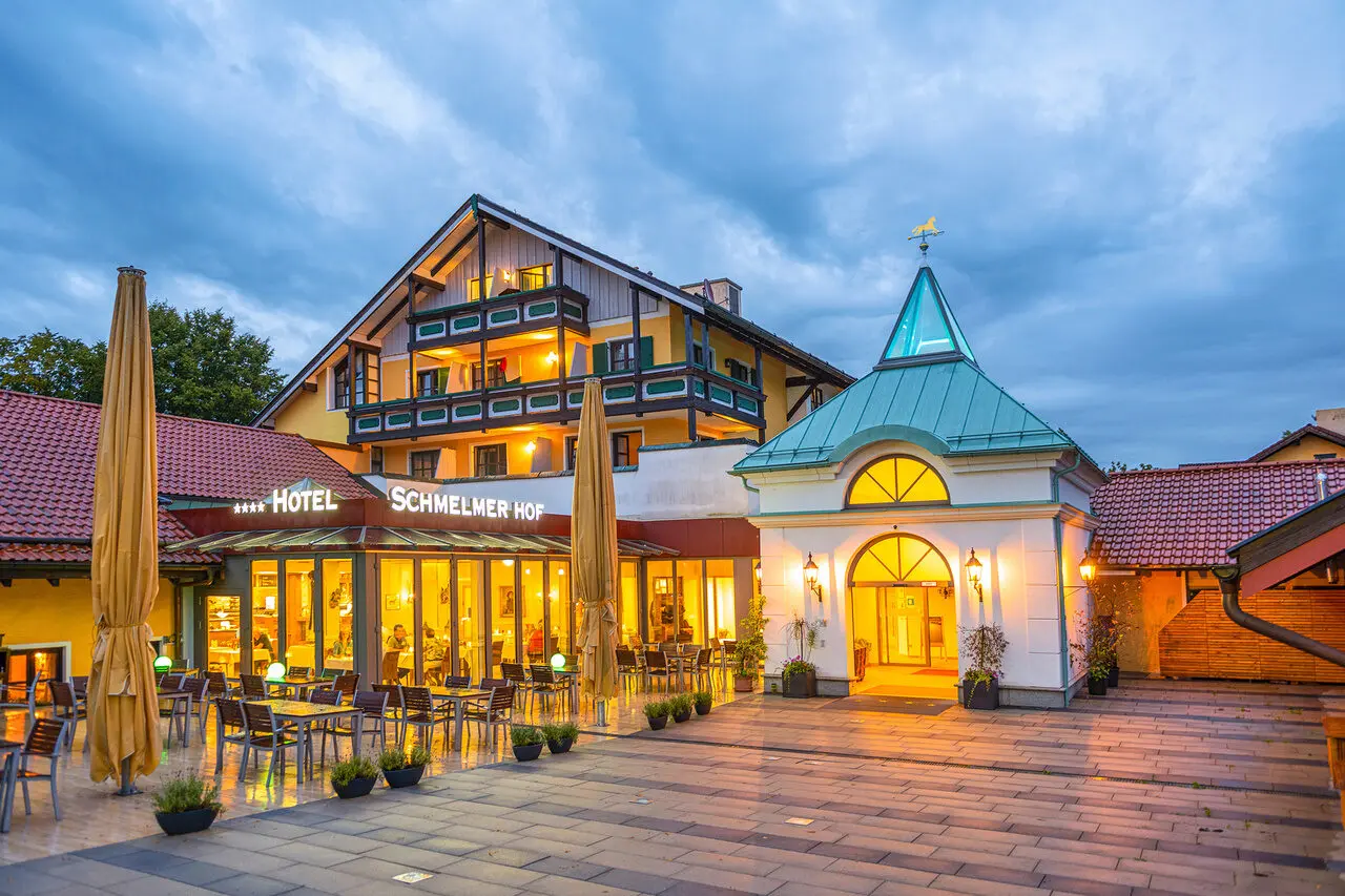 Abendansicht des Hotels Schmelmer Hof mit beleuchteter Fassade, Eingangsbereich und Aussenrestaurant.