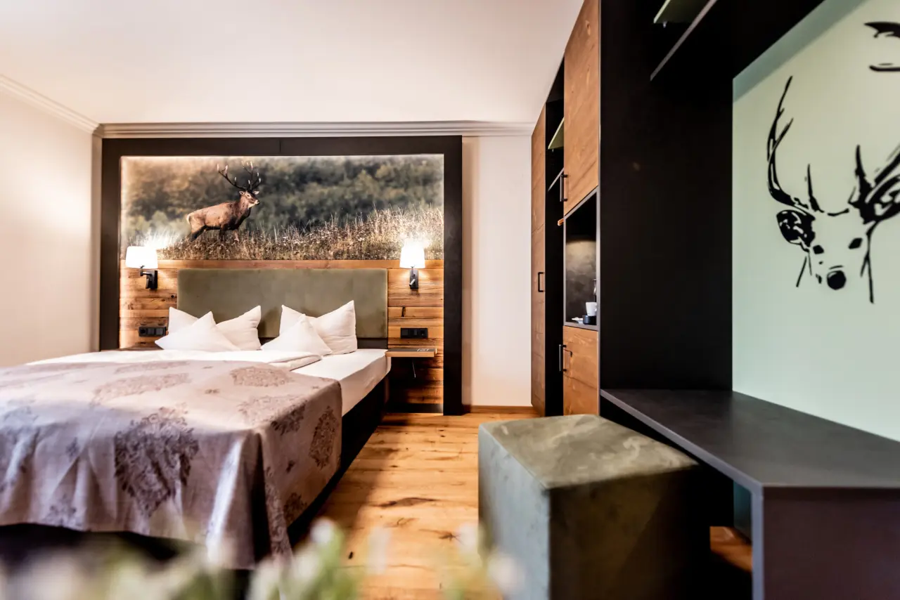 Komfortables Doppelzimmer im Hotel Schmelmer Hof mit stilvollem Hirschmotiv, Holzakzenten und gemütlicher Atmosphäre.