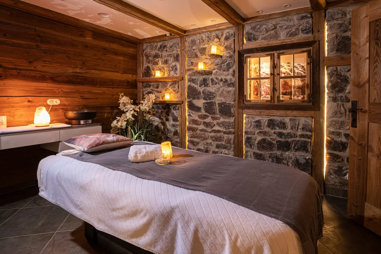 Gemütlicher Behandlungsraum im Spa des Hotel Schmelmer Hof mit Massageliege, Salzlampe und rustikalem Alpen-Flair.
