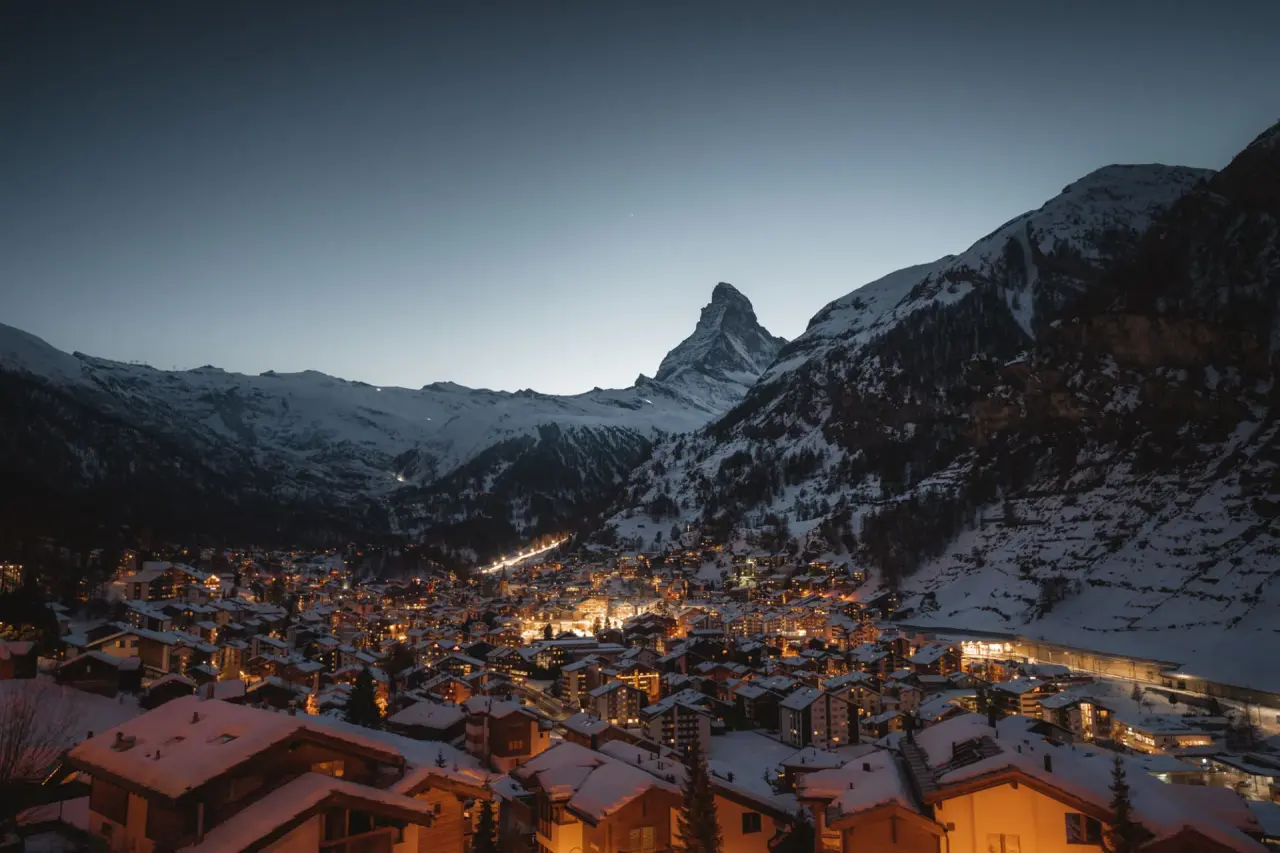 Panoramablick auf das beleuchtete Bergdorf Zermatt mit Matterhorn bei Dämmerung, Alpen Resort Hotel.