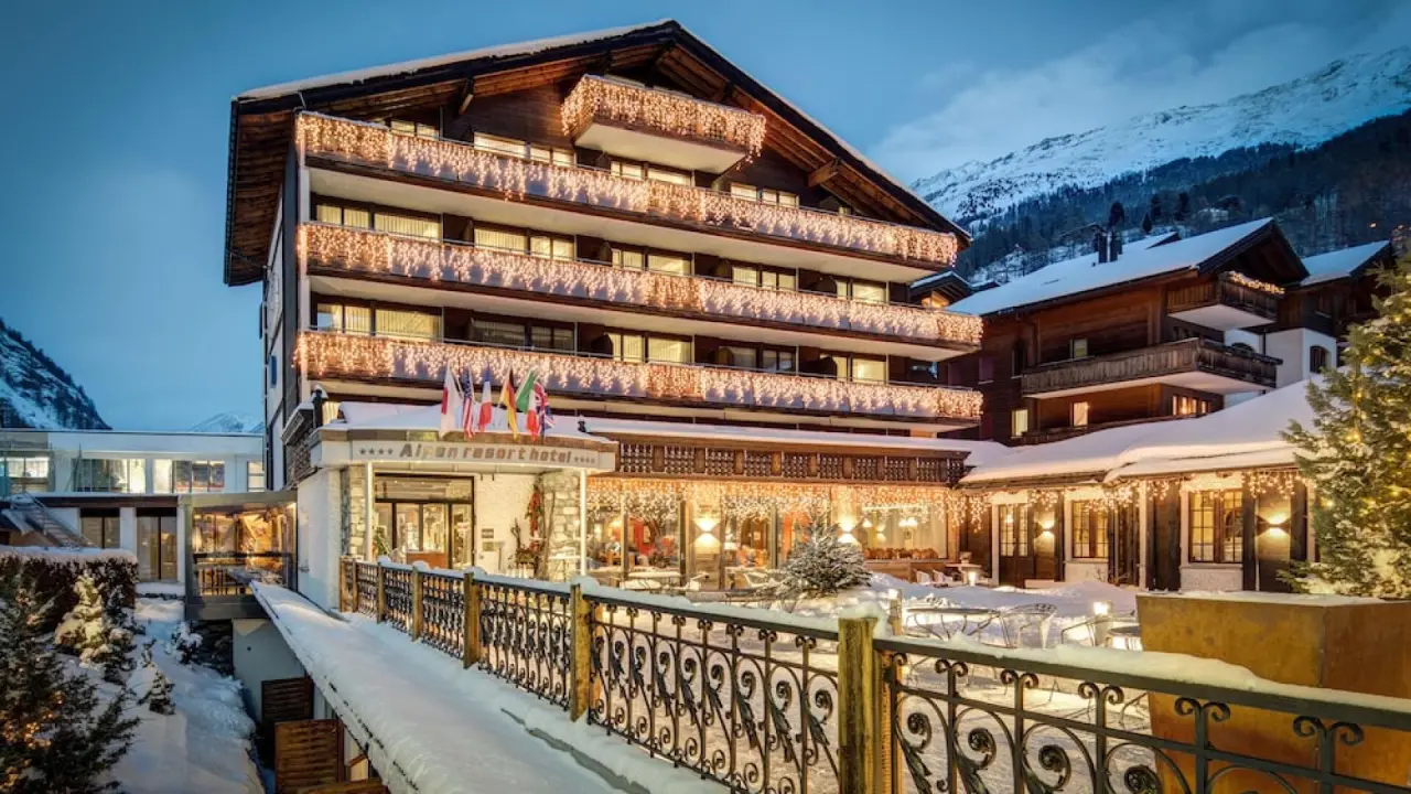 Festlich beleuchtetes Alpen Resort Hotel im Winter, umgeben von Schnee und alpiner Bergkulisse. Ideal für einen Wellnessurlaub.