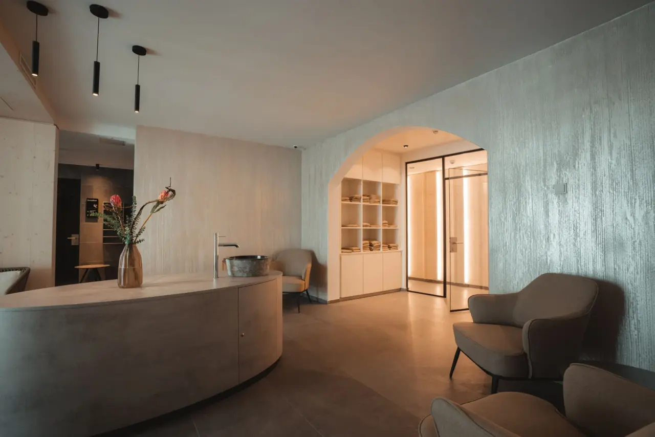Modern gestalteter Spa-Empfangsbereich mit Rezeption, Sitzgelegenheiten und Handtuchregalen im Alpen Resort Hotel.