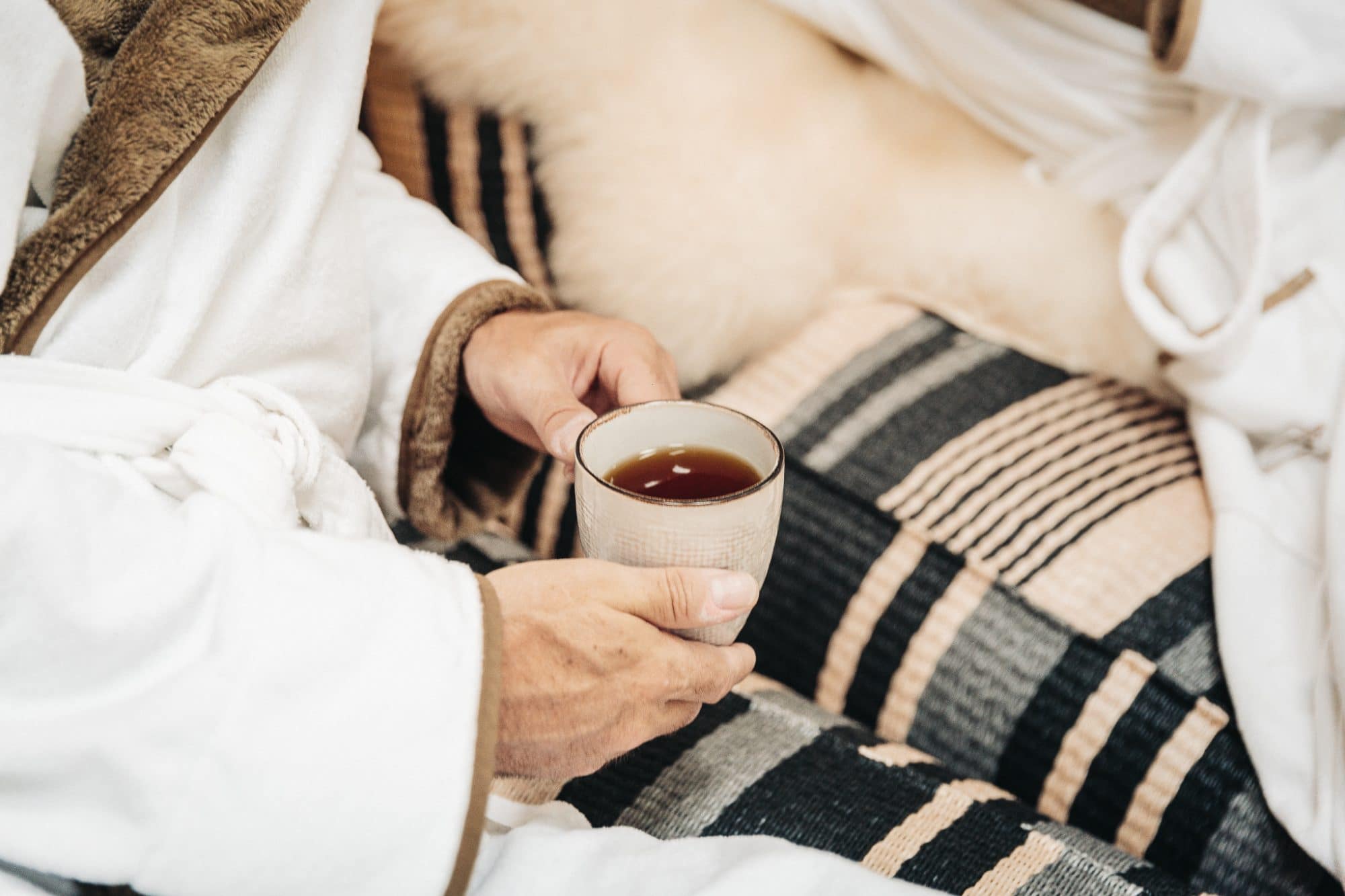 Das Mühlbach Thermal Spa in Bad Füssing – Gast im Bademantel mit Teetasse | Wellnesshotel Bad Füssing