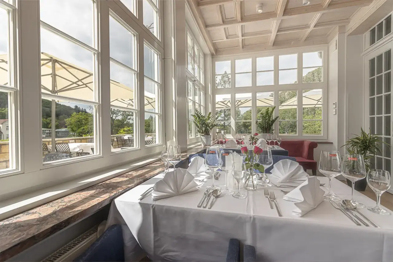 Elegantes Restaurant mit großen Fenstern und Blick ins Grüne im Sonnenresort ETTERSHAUS, perfekt für genussvolle Mahlzeiten.
