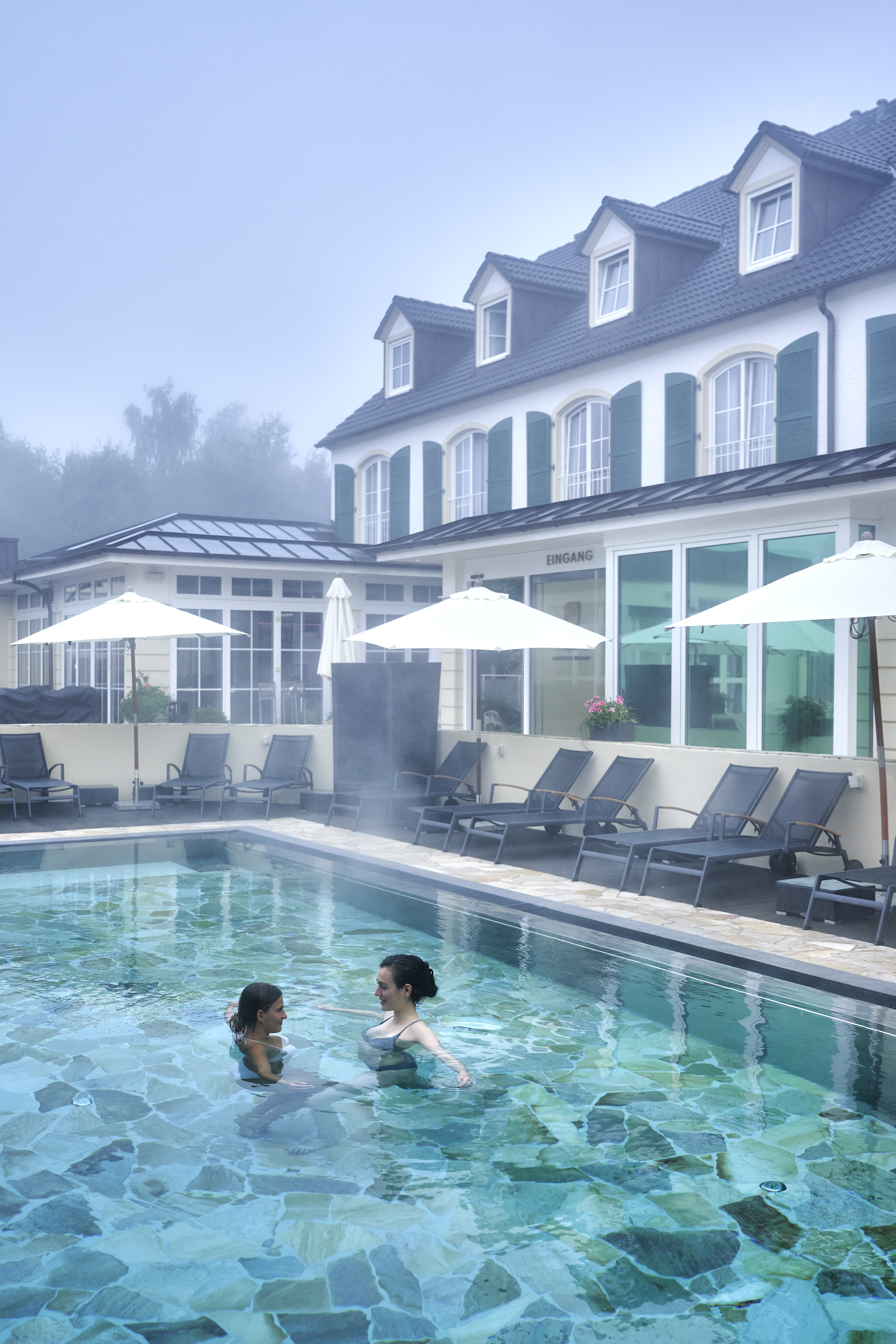 Lifestyle Resort Zum Kurfürsten in Bernkastel-Kues – Außenpool mit Badegästen im Nebel | Wellnesshotel Mosel