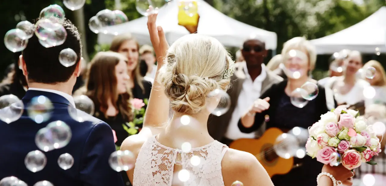 Fröhliche Hochzeitsfeier im Freien mit Seifenblasen und Blumenstrauß im Freund Das Hotel & Natur Resort.