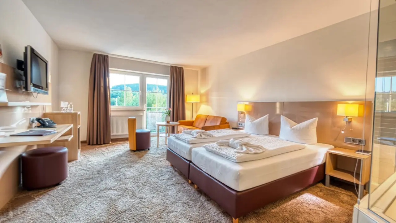 Komfortables Doppelzimmer im Hotel & SPA Reibener-Hof mit gemütlichem Sitzbereich, Schreibtisch und Blick ins Grüne.