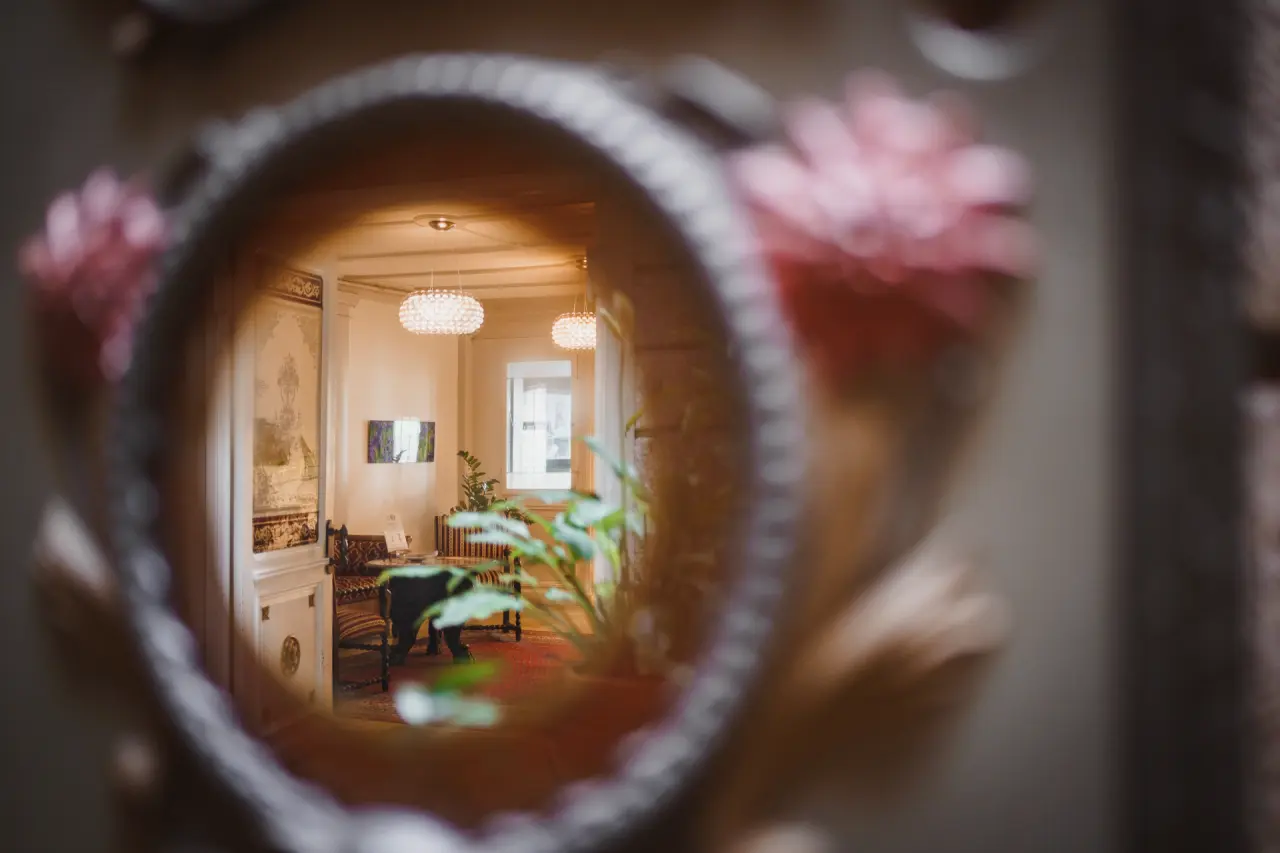 Blick durch einen dekorativen Spiegel in die gemütliche Lobby des BLUME. Baden Hotel & Restaurant.