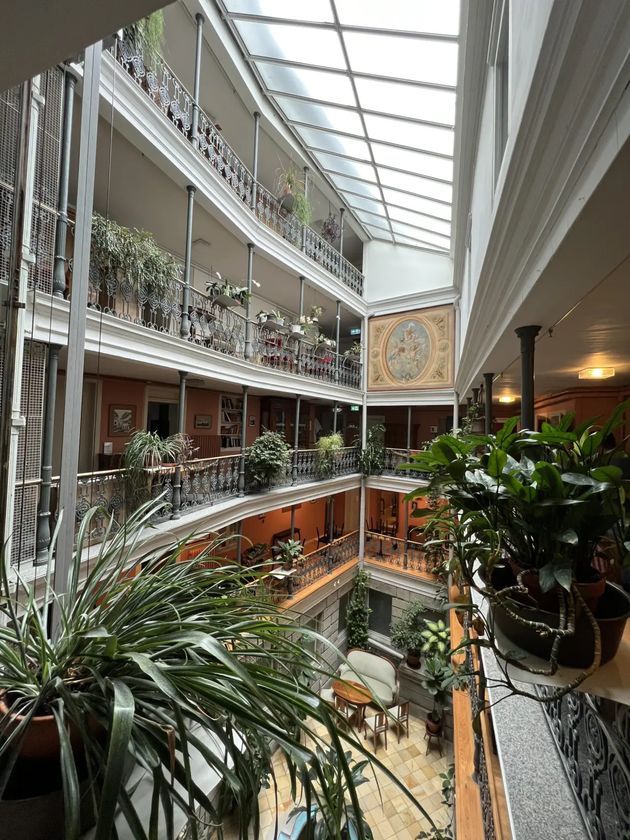 Mehrstöckiges Atrium mit Glasdach und üppigen Pflanzen im BLUME. Baden Hotel & Restaurant.