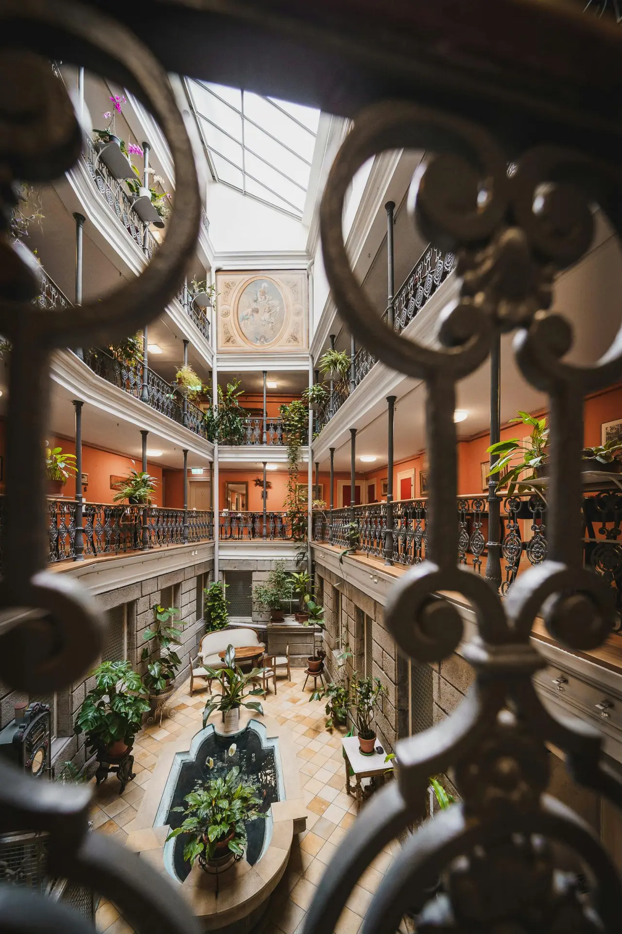 Historischer Innenhof mit Glasdach, Pflanzen und Springbrunnen im BLUME. Baden Hotel & Restaurant.