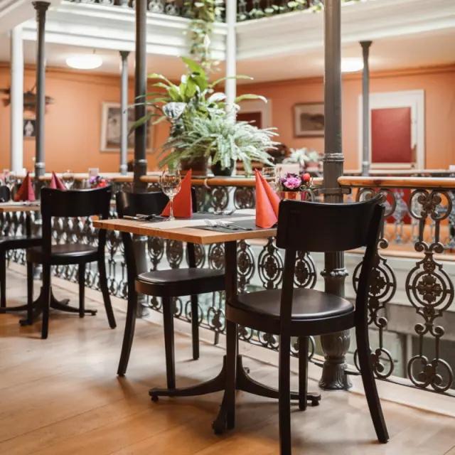 Gedeckter Tisch im Restaurant des BLUME. Baden Hotel & Restaurant mit historischem Balkon und Pflanzen.