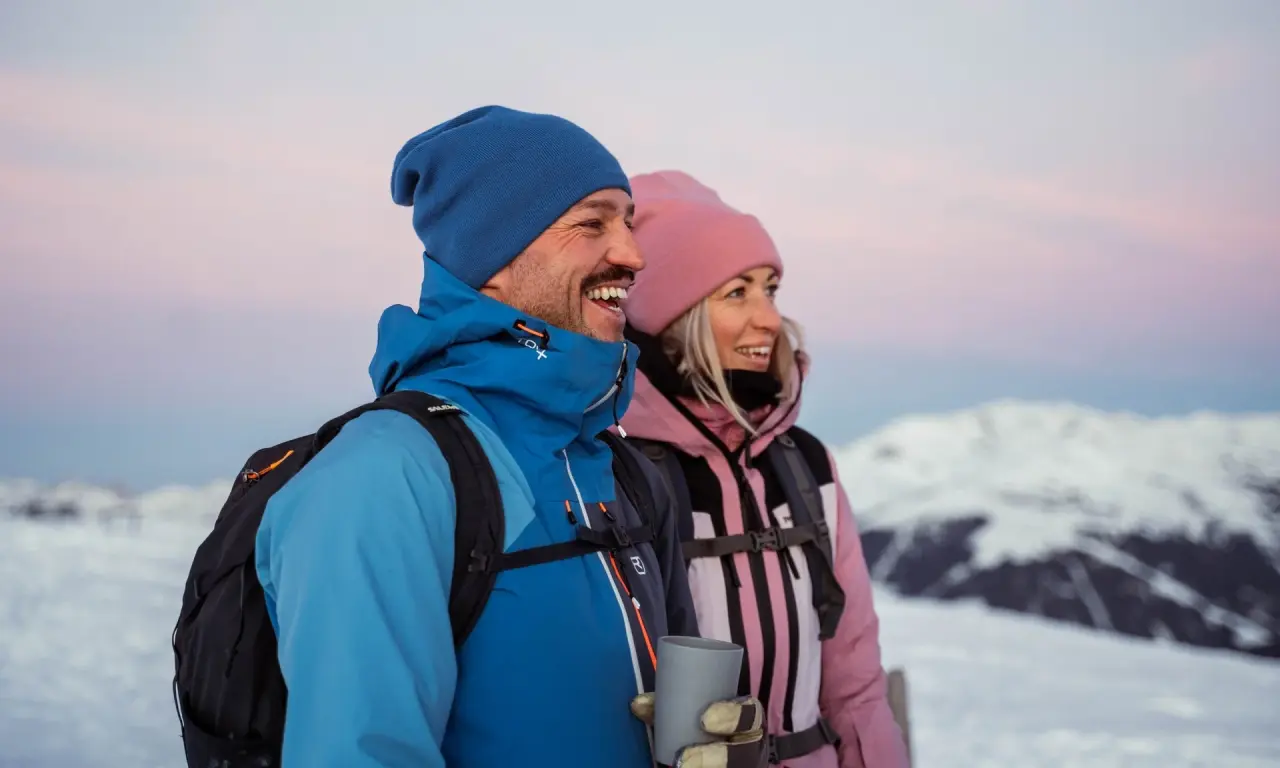 Glückliches Paar beim Winterwandern in verschneiter Berglandschaft bei Sonnenaufgang, Hotel Gassner.