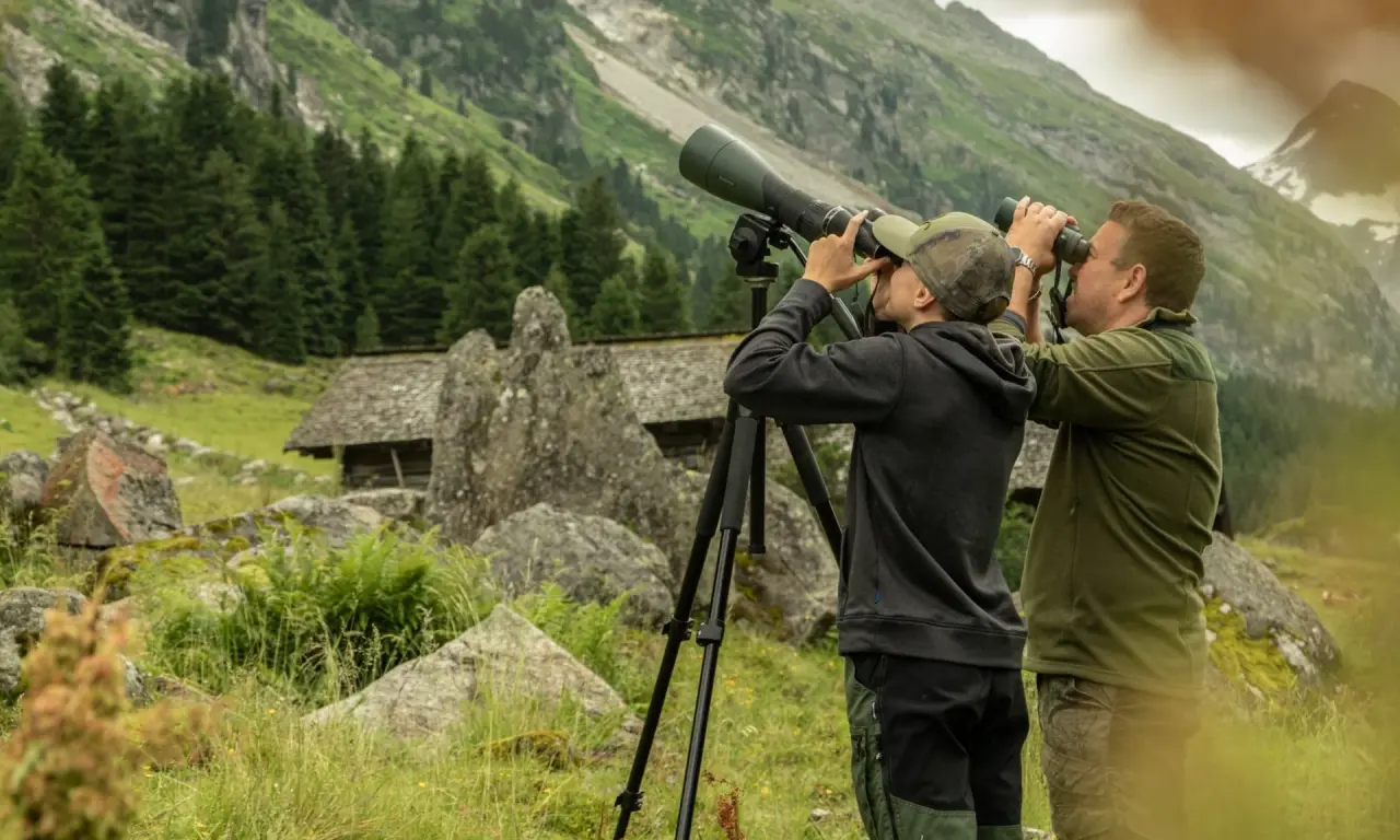 Zwei Personen beobachten mit Fernglas und Spektiv die Bergwelt rund um das Hotel Gassner 4 Sterne Superior.
