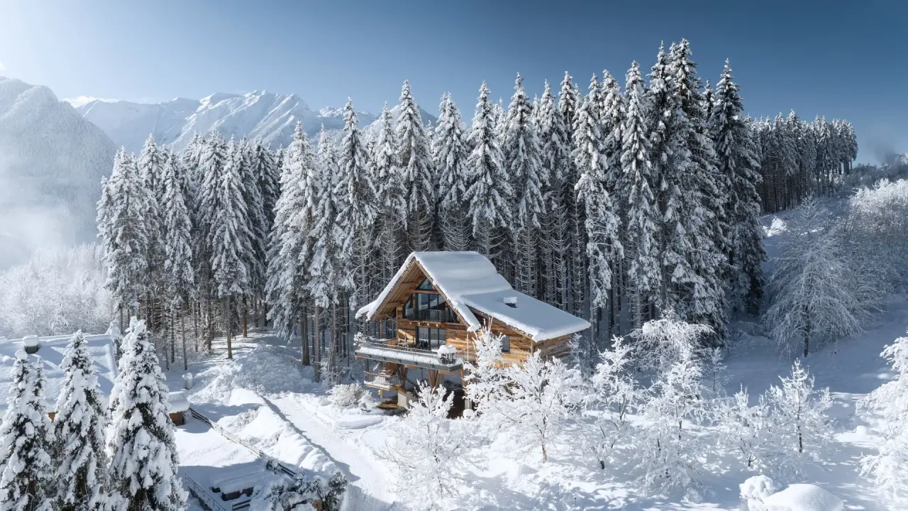 Luxuriöses Chalet des Hotel Gassner 4 Sterne Superior im verschneiten Winterwald mit Bergpanorama.