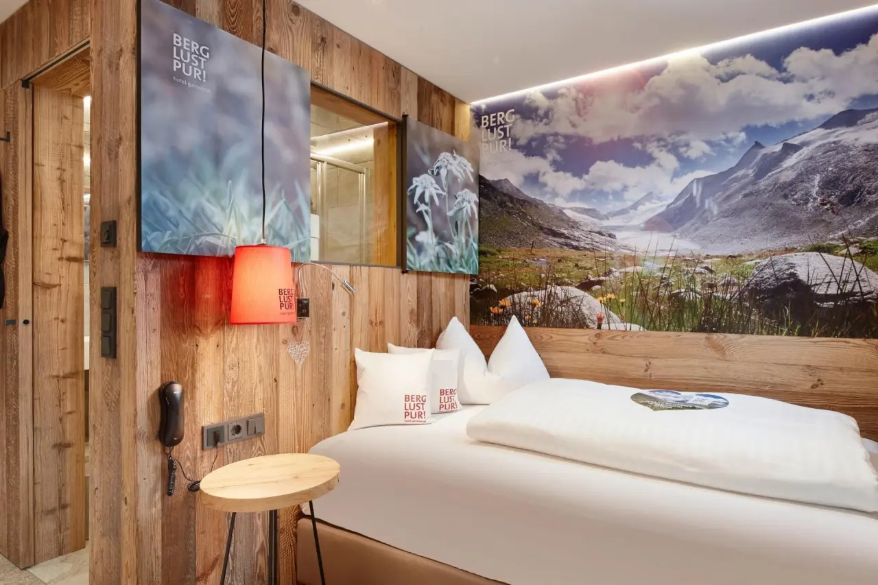 Gemütliches Doppelzimmer im alpinen Stil mit Holzwänden und Bergpanorama-Wandbild im Hotel Gassner 4 Sterne Superior.