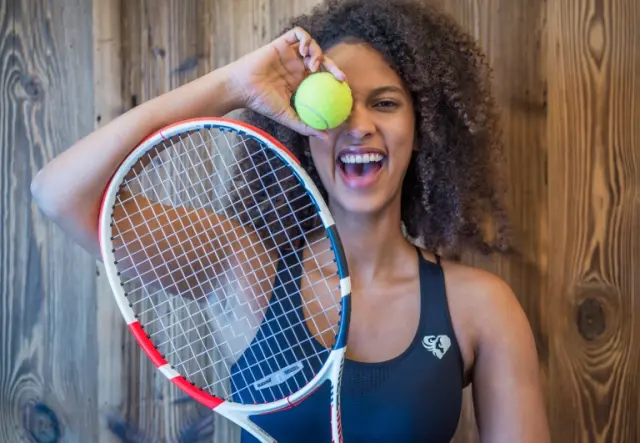 Lachende Frau mit Tennisschläger und Ball im Ortner's Resort
