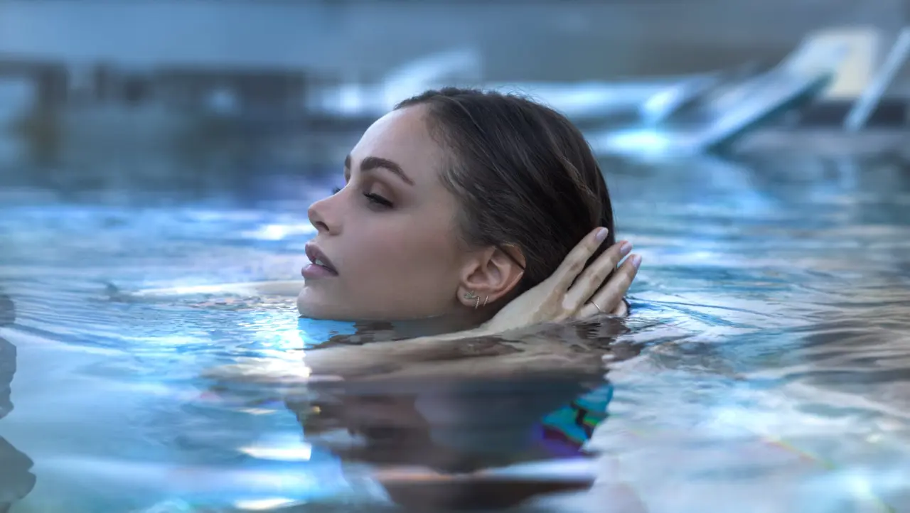 Junge Frau entspannt im warmen Wasser des Pools im Ortner's Resort. Ein Moment der Ruhe und Erholung im Wellnessbereich.