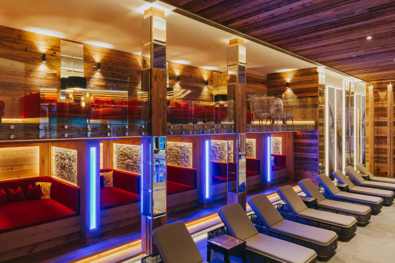 Moderner Ruheraum im Spa-Bereich des Ortner's Resort mit Holzvertäfelung, bequemen Liegen und blauer LED-Beleuchtung.