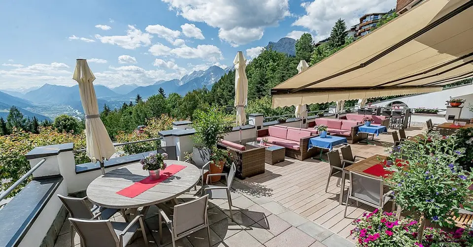 Sonnige Panoramaterrasse des Inntalerhof - DAS Panoramahotel mit bequemen Sitzgelegenheiten und atemberaubendem Bergblick.