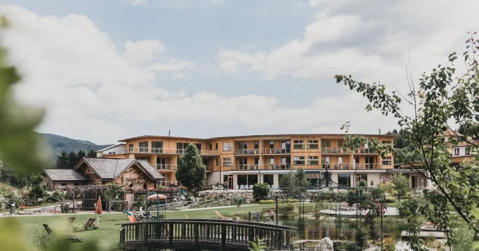 Aussenansicht des Wellnesshotels Molzbachhof mit Naturteich, Garten und Holzfassaden in idyllischer Landschaft.