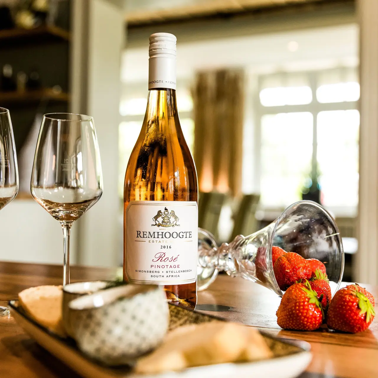 Flasche Roséwein, Weingläser, Erdbeeren und Snacks auf Holztisch im Lundenbergsand Nordsee Hideaway und Spa.