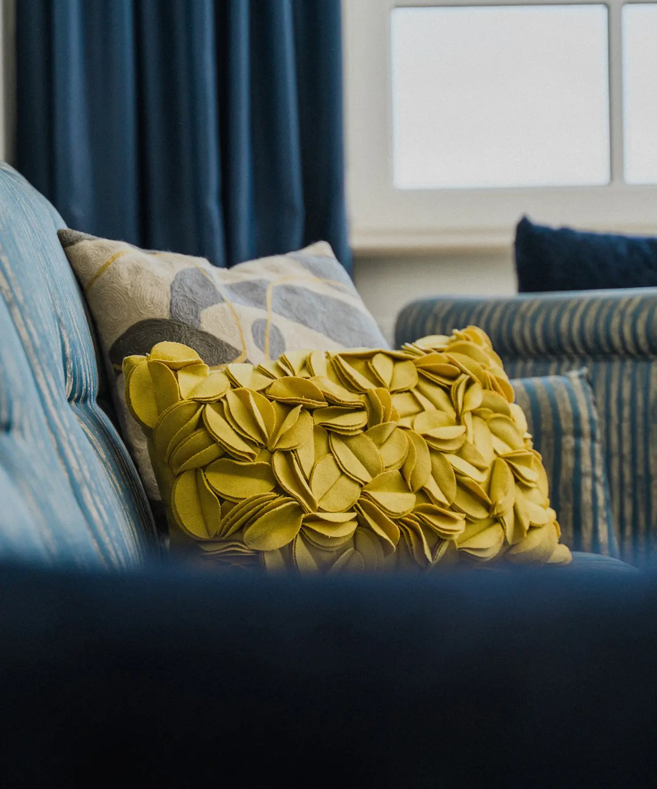 Detailaufnahme von blauen und gelben Zierkissen auf einem Sofa im Lundenbergsand Nordsee Hideaway und Spa.