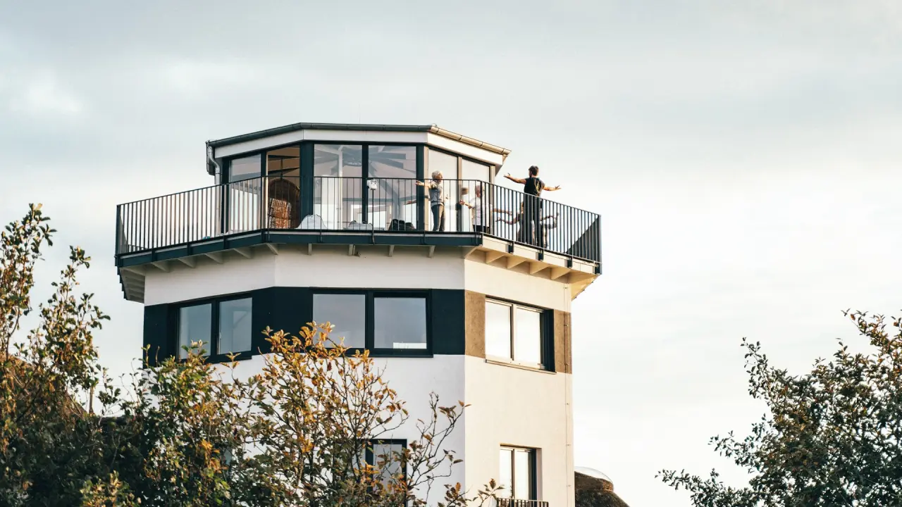 Gäste beim Yoga auf dem Turmbalkon des Lundenbergsand Nordsee Hideaway und Spa mit Blick über die Landschaft.