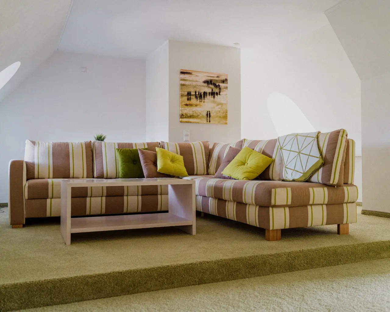 Gemütliche Sitzecke mit gestreiftem Sofa und Couchtisch in einer Suite im Lundenbergsand Nordsee Hideaway und Spa.